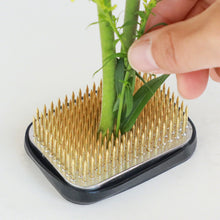 Load image into Gallery viewer, hand sticking a flower stem on the rectangular kenzan
